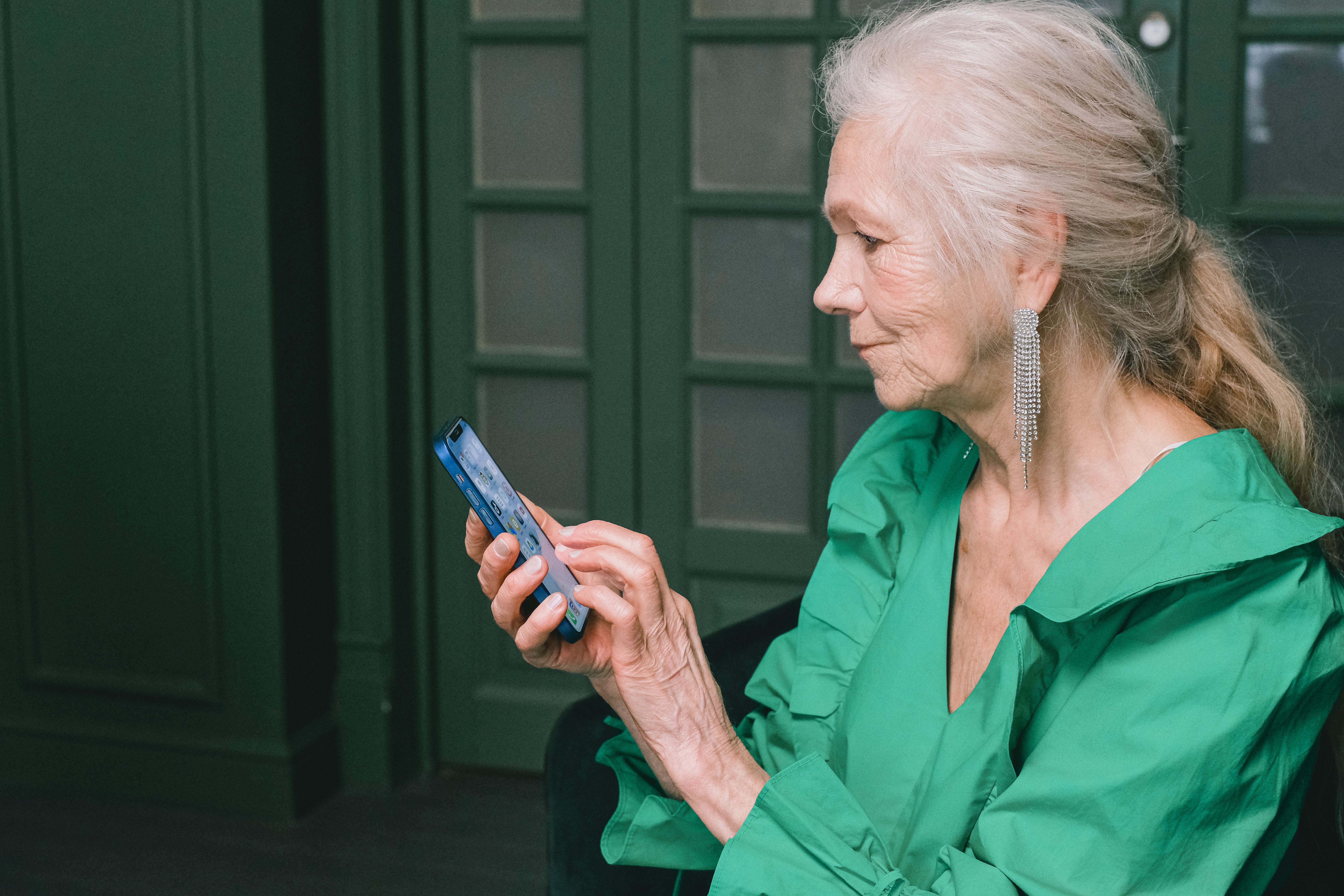 Mulher idosa usando smartphone com expressão tranquila e confiante