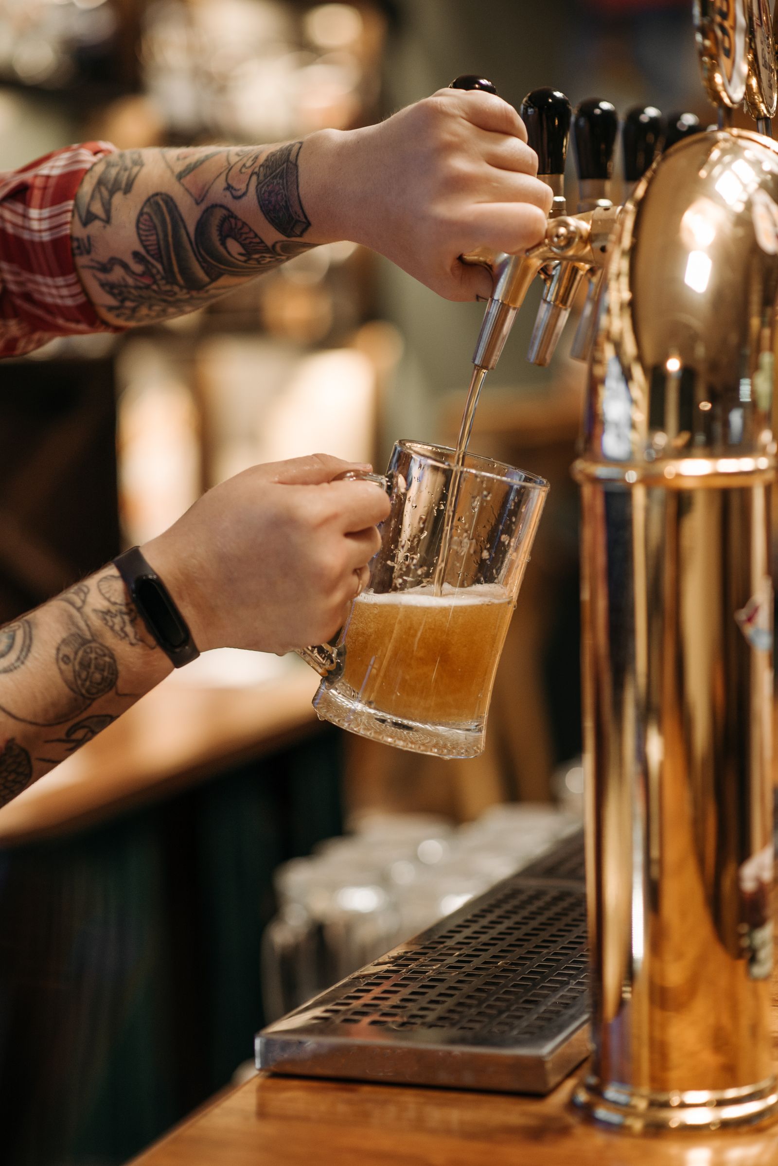 Bartender tatuado servindo chope em bar movimentado durante os jogos da Copa do Mundo