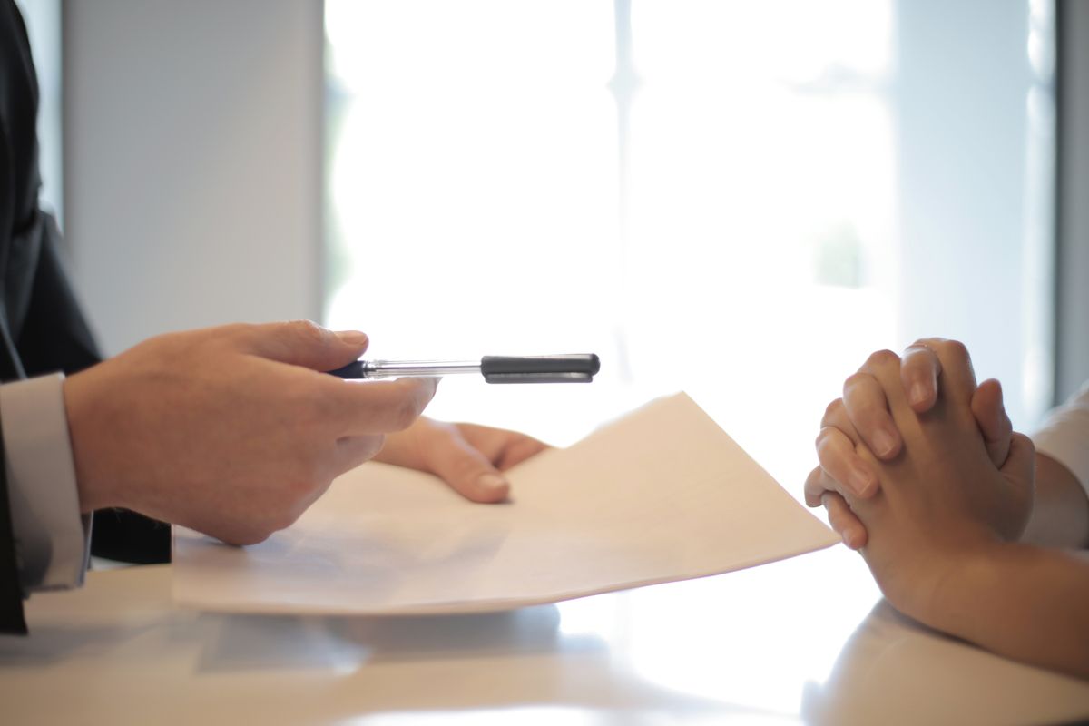 Atendente entrega caneta para cliente assinar contrato de crédito consignado