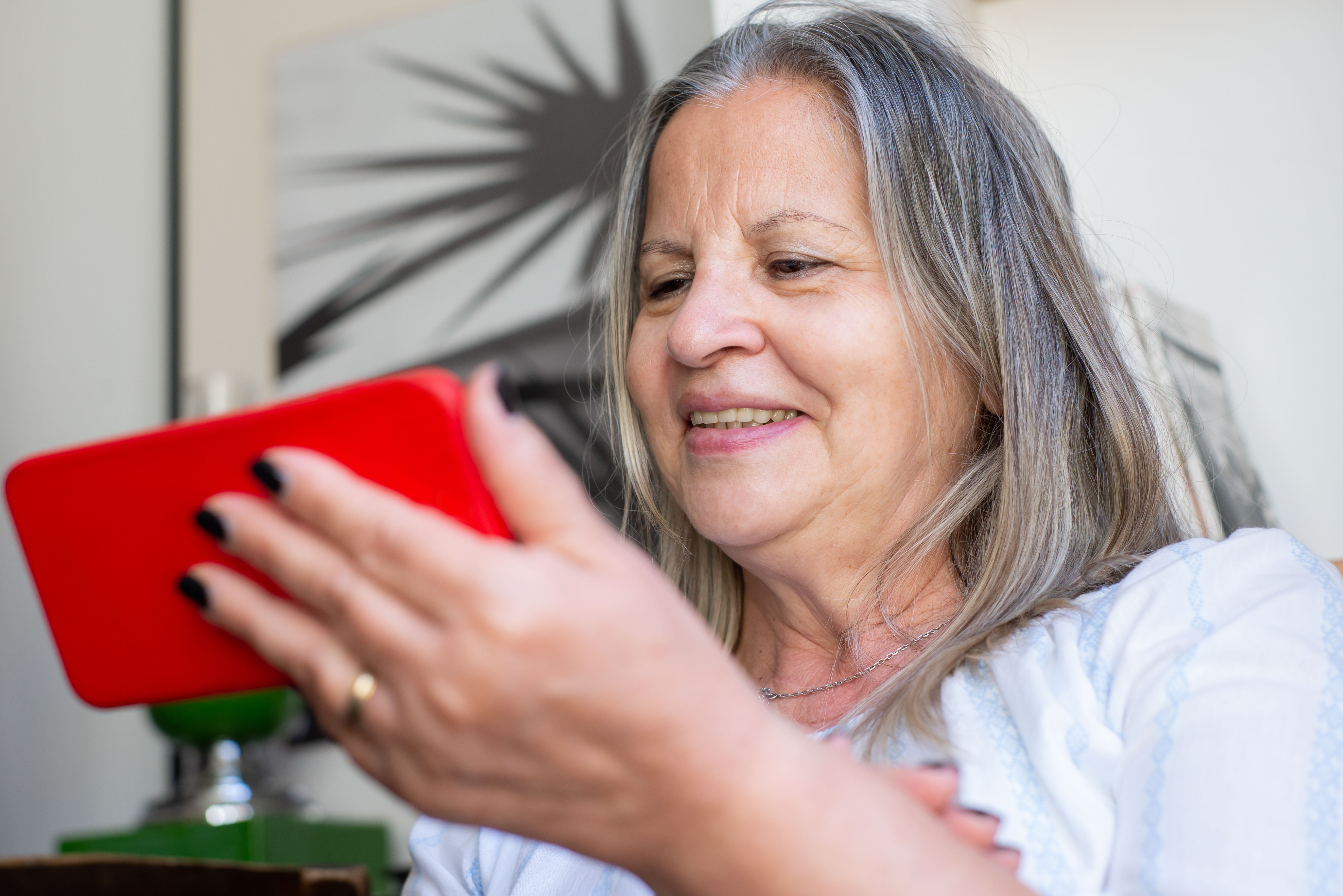 Senhora idosa sorrindo enquanto olha para a tela do celular