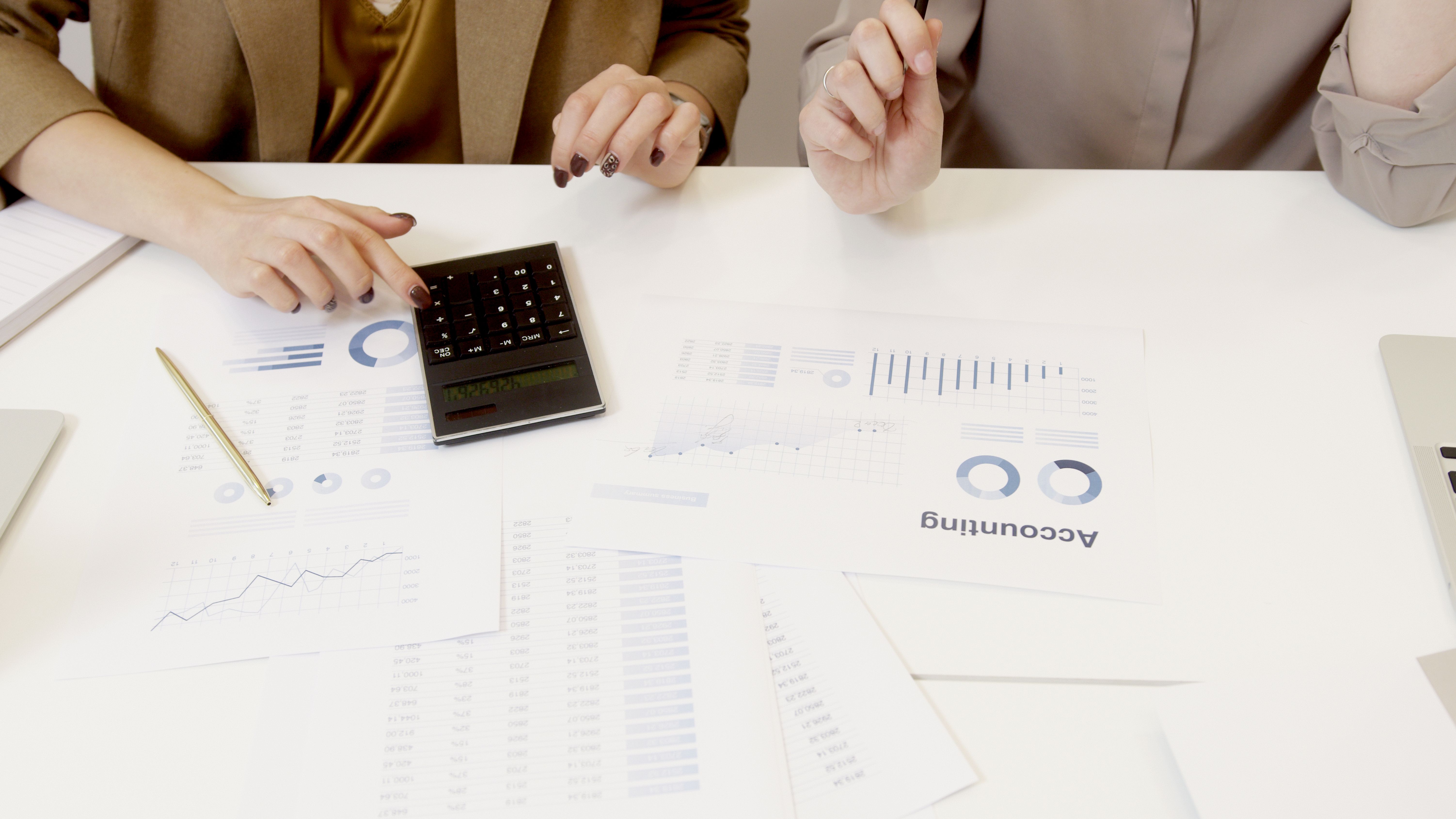 Duas profissionais de contabilidade analisando relatórios financeiros e calculadora sobre a mesa