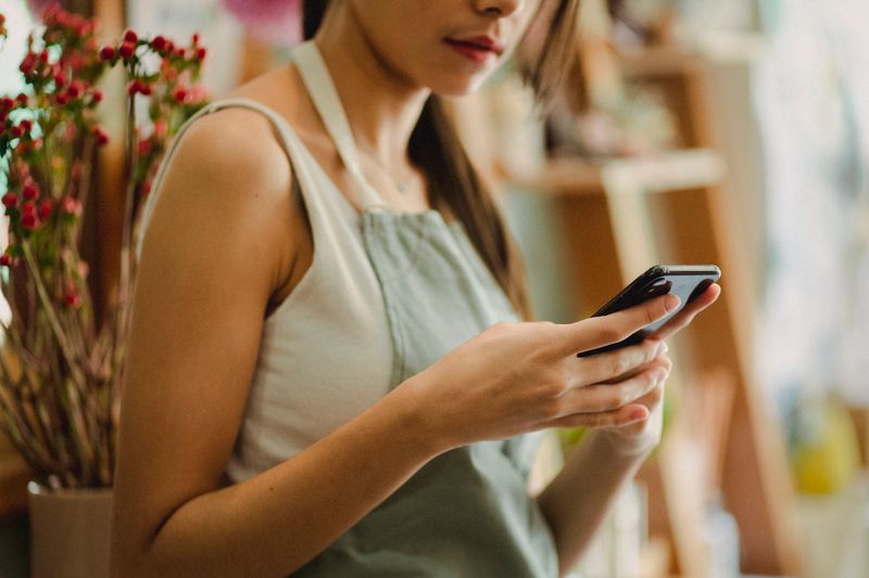 Empreendedora usando o celular em uma pequena loja, representando o MEI que precisa formalizar a renegociação do Desenrola Empresas