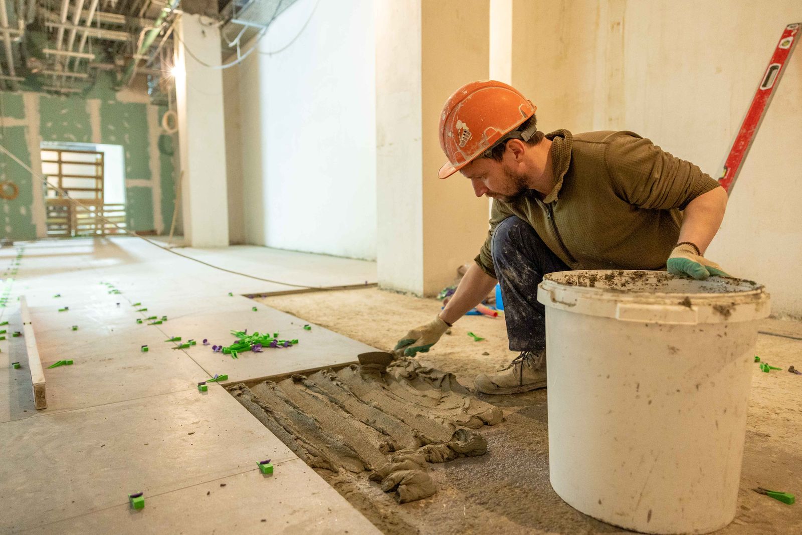 Trabalhador da construção civil assentando piso com argamassa durante reforma residencial
